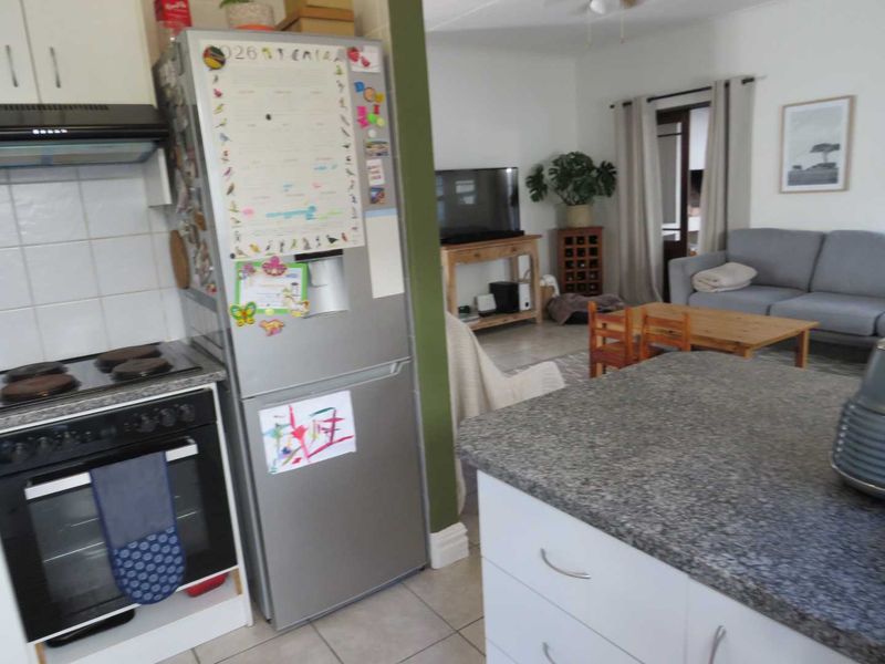 Open-plan kitchen and living area featuring tiled floors, granite countertops, and built-in cabinetry, creating a functional and connected living space.