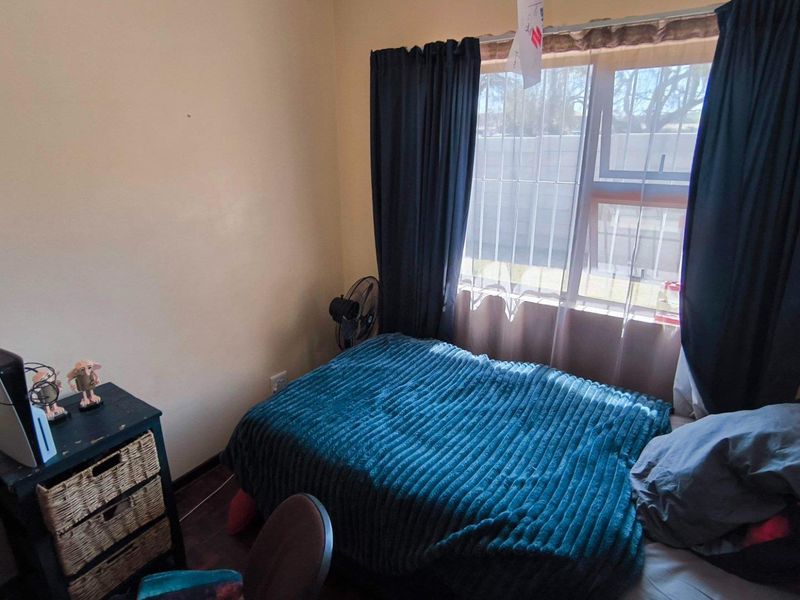 A compact bedroom featuring a window with curtain rails and neutral wall finishes.