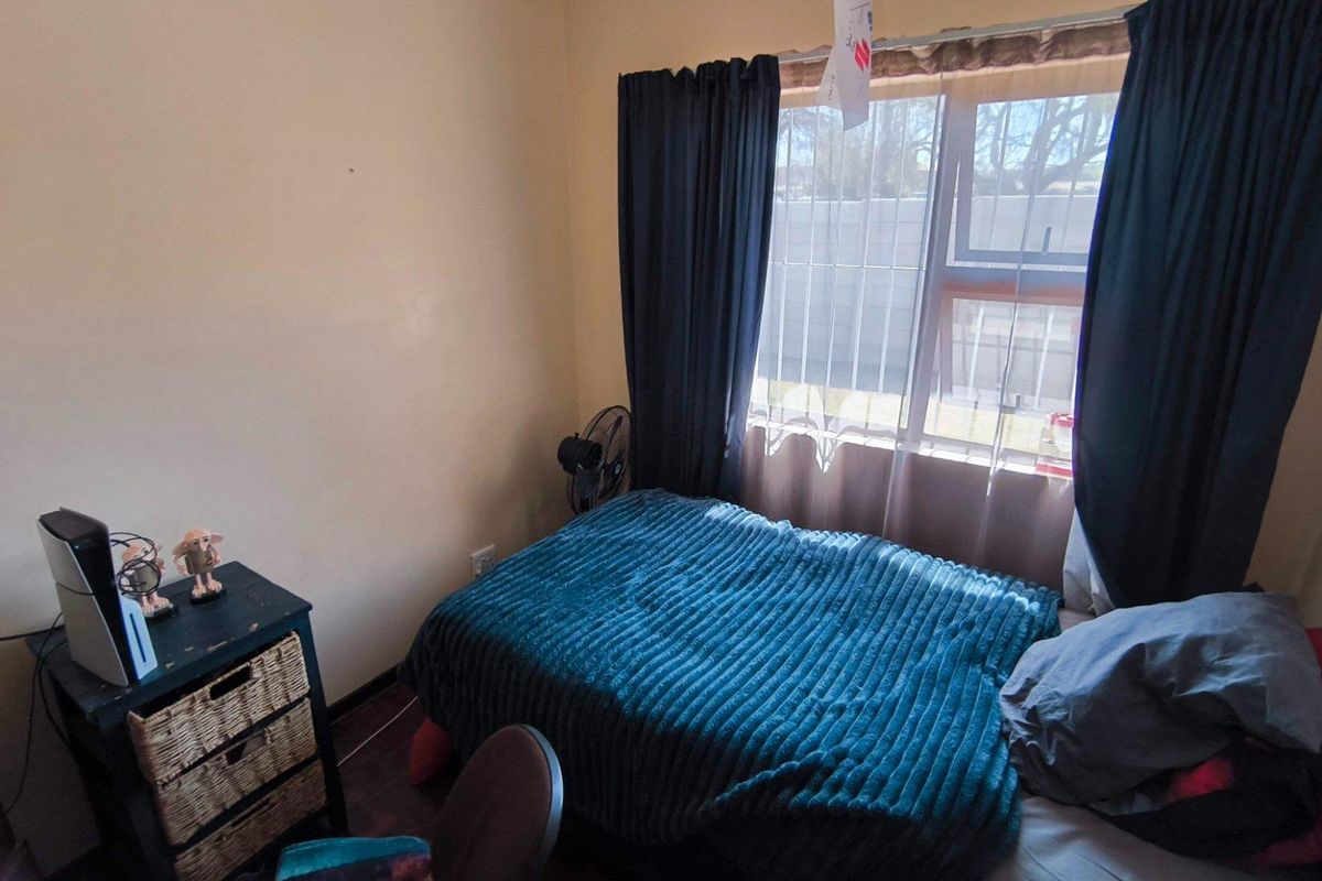 A compact bedroom featuring a window with curtain rails and neutral wall finishes.