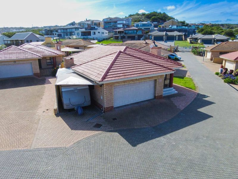 Aerial view of a residential townhouse property featuring a tiled roof, brick exterior, double garage, and paved driveway within a suburban estate.