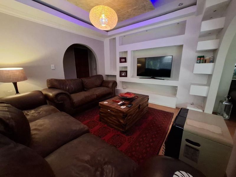 A comfortable living room featuring custom built-in shelving, recessed ceiling lighting, and a decorative archway leading to adjacent spaces.