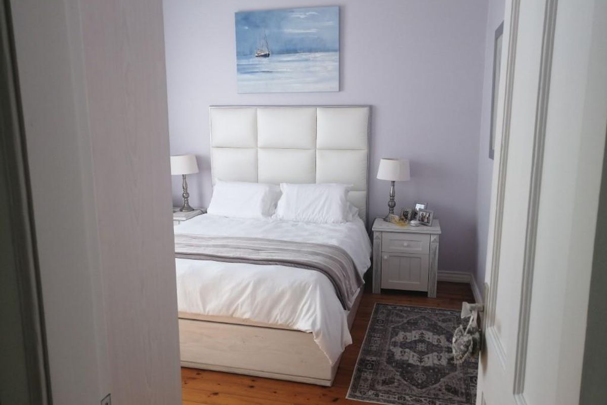 A well-maintained bedroom featuring polished timber flooring and a neutral color palette, viewed from the doorway.
