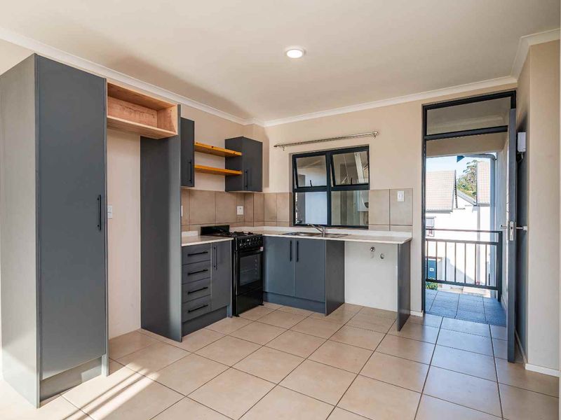 Modern kitchen featuring dark grey cabinetry, tiled flooring, a built-in stove, and direct access to an outdoor balcony area.