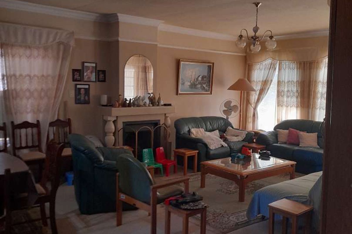 A spacious living room featuring a traditional fireplace with a mantelpiece, decorative coving, and an archway entrance.