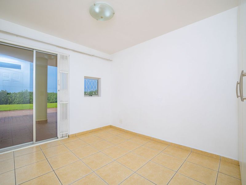 An empty bedroom featuring tiled flooring, a built-in wardrobe, and a sliding glass door providing access to an outdoor patio area.