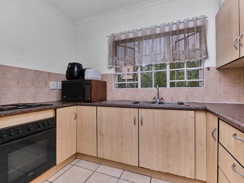 Functional kitchen featuring laminate cabinetry, tiled backsplash, built-in oven, ceramic hob, and a stainless steel double sink with window views.