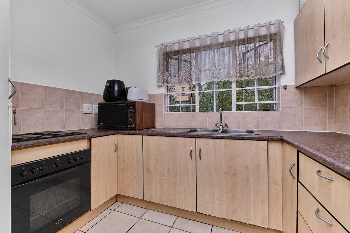 Functional kitchen featuring laminate cabinetry, tiled backsplash, built-in oven, ceramic hob, and a stainless steel double sink with window views.
