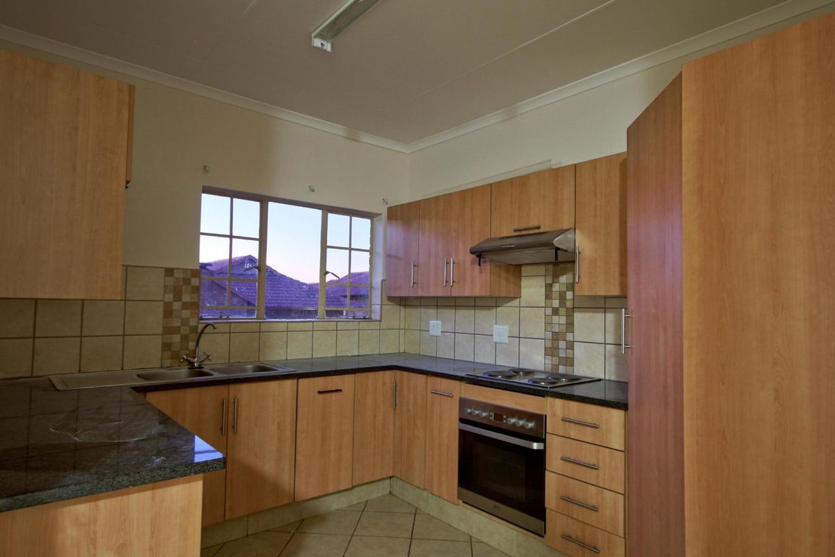 A functional kitchen featuring laminate cabinetry, granite countertops, built-in oven, electric hob, and tiled backsplash, offering a clean and practical workspace.