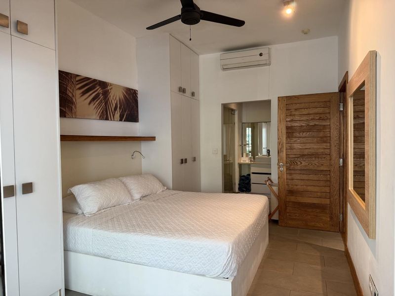 A well-maintained bedroom featuring built-in cupboards, a ceiling fan, split-system air conditioning, and direct access to an en-suite bathroom.