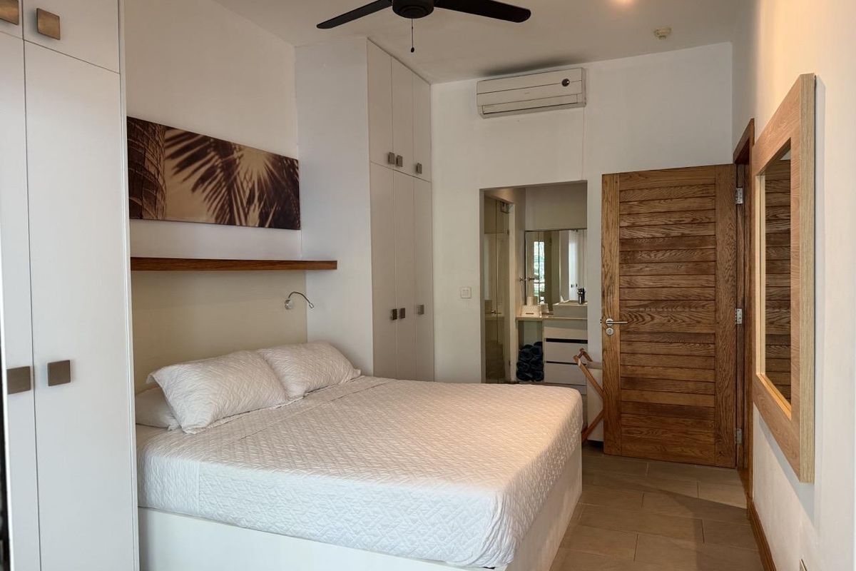 A well-maintained bedroom featuring built-in cupboards, a ceiling fan, split-system air conditioning, and direct access to an en-suite bathroom.