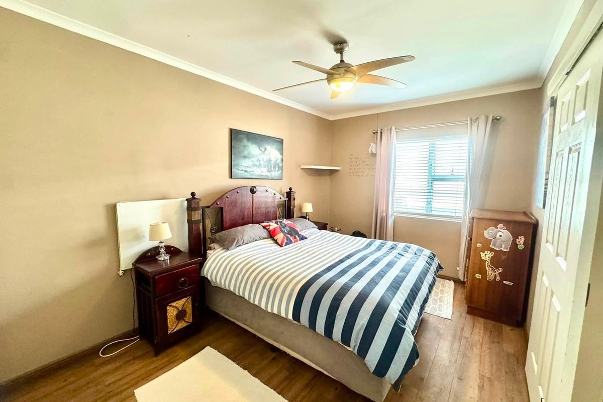 A functional bedroom featuring laminate flooring, a ceiling fan, and built-in storage, offering a comfortable and practical living space.