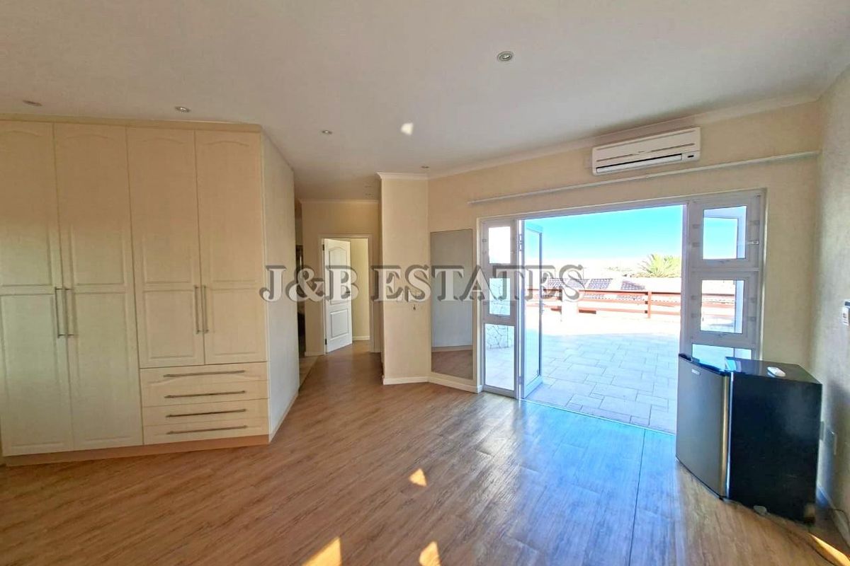 Spacious bedroom featuring built-in cabinetry, wood-look flooring, and direct access to a private outdoor patio area through glass doors.
