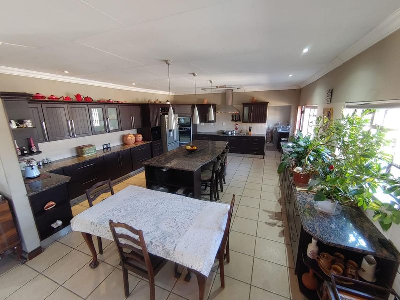 Spacious kitchen featuring dark wood cabinetry, granite countertops, a large central island, and tiled flooring, offering ample workspace and storage.