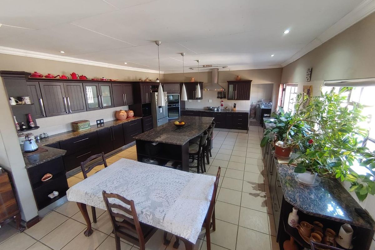 Spacious kitchen featuring dark wood cabinetry, granite countertops, a large central island, and tiled flooring, offering ample workspace and storage.
