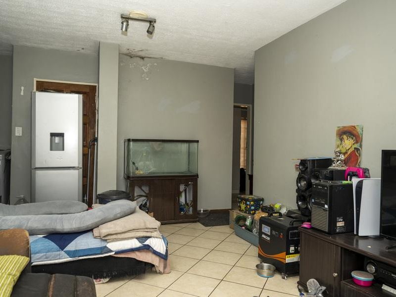A living area featuring tiled flooring and visible ceiling water damage, requiring maintenance and cosmetic updates.