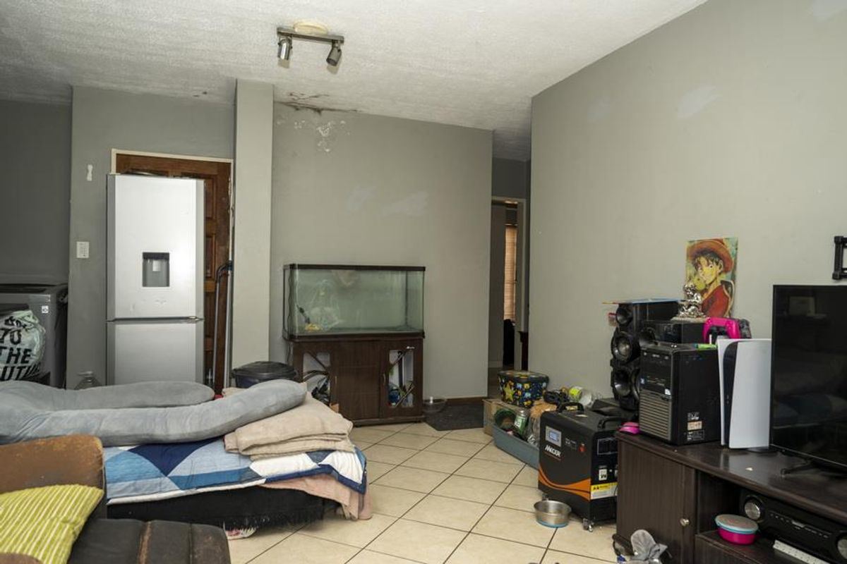 A living area featuring tiled flooring and visible ceiling water damage, requiring maintenance and cosmetic updates.