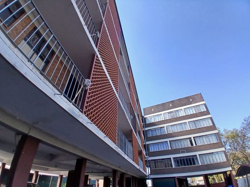 Exterior view of a multi-story apartment building featuring brick facades, metal balcony railings, and distinctive terracotta breeze block architectural detailing.