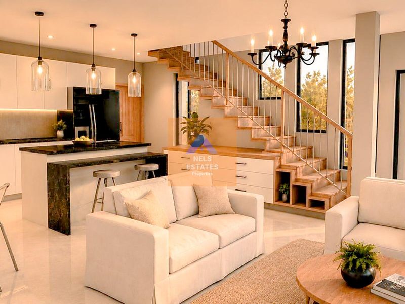 Modern open-plan living area featuring a sleek kitchen with stone island, elegant staircase with integrated storage, and bright, contemporary finishes throughout.