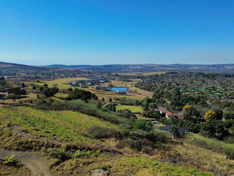 An elevated aerial view showcasing the surrounding landscape, residential neighborhood, and natural terrain of the vacant land property.