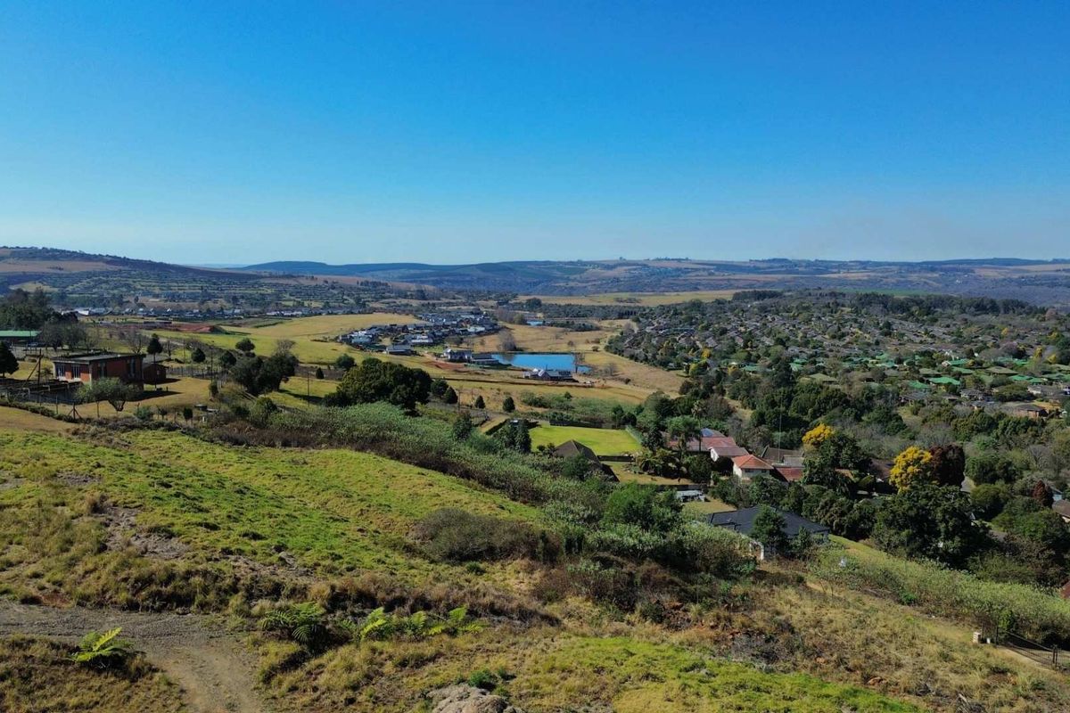 An elevated aerial view showcasing the surrounding landscape, residential neighborhood, and natural terrain of the vacant land property.