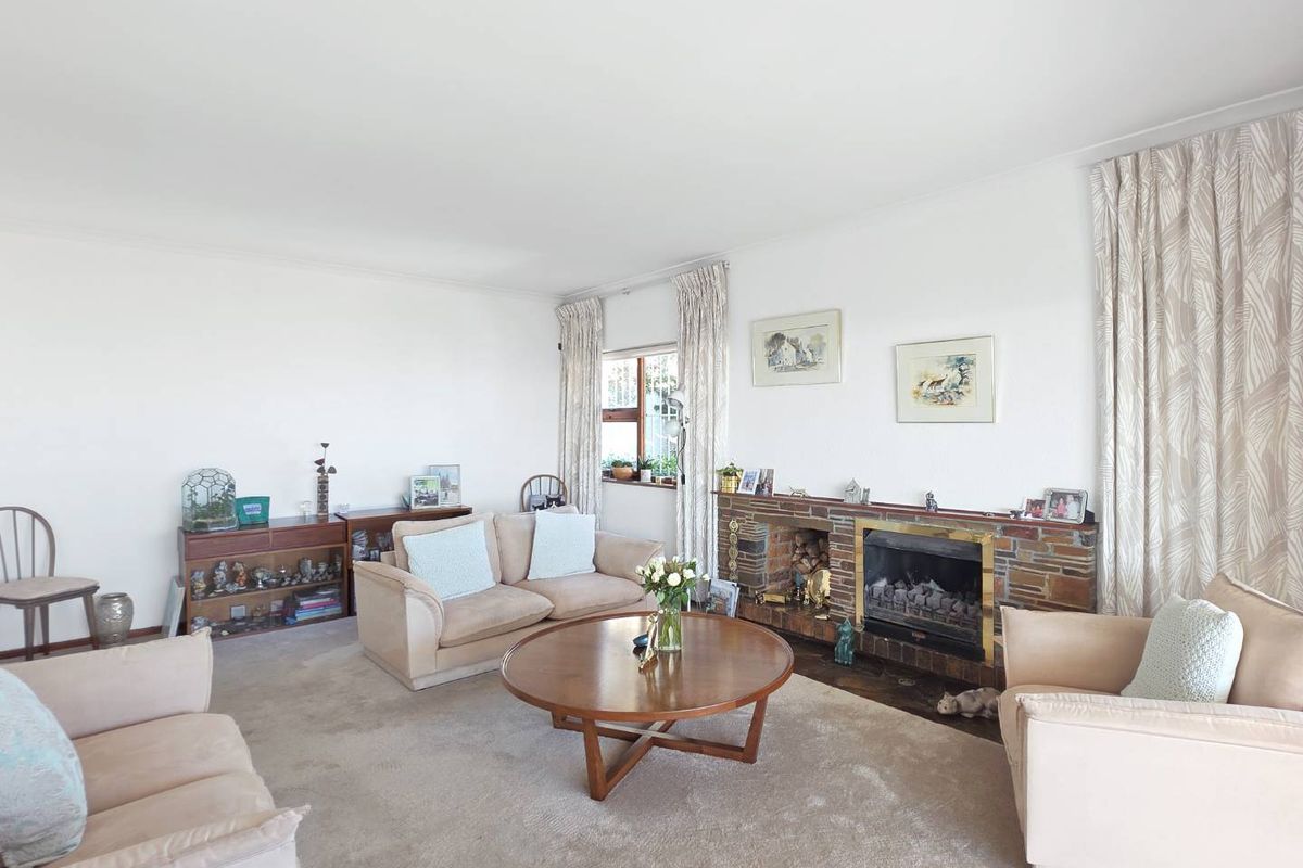A spacious living room featuring a traditional brick fireplace and neutral carpeting, offering a comfortable and classic layout.