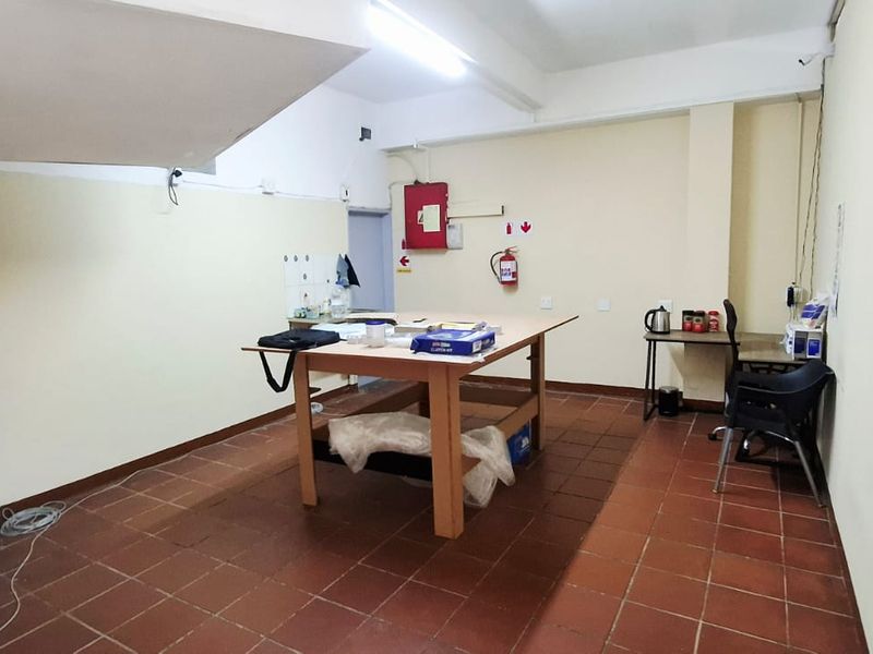 A functional utility or storage space featuring tiled flooring, overhead fluorescent lighting, and essential fire safety equipment.