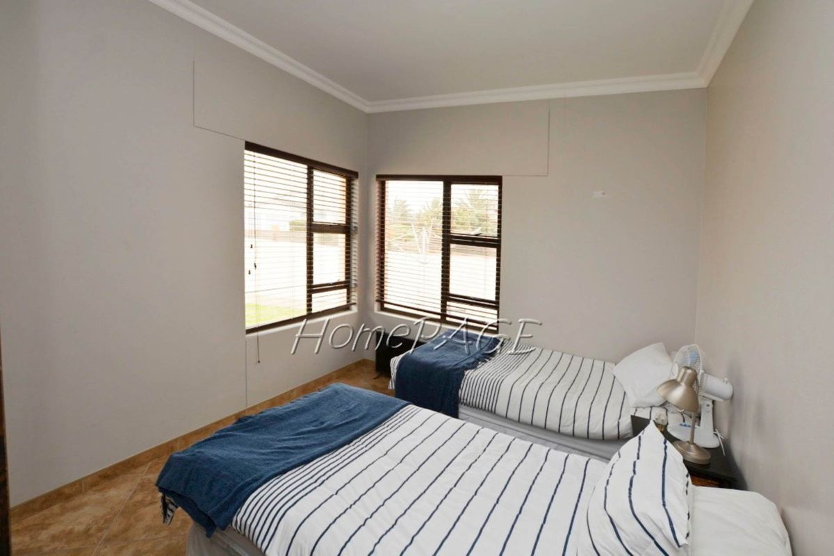 A bedroom featuring tiled flooring, corner windows with fitted blinds, and crown molding.