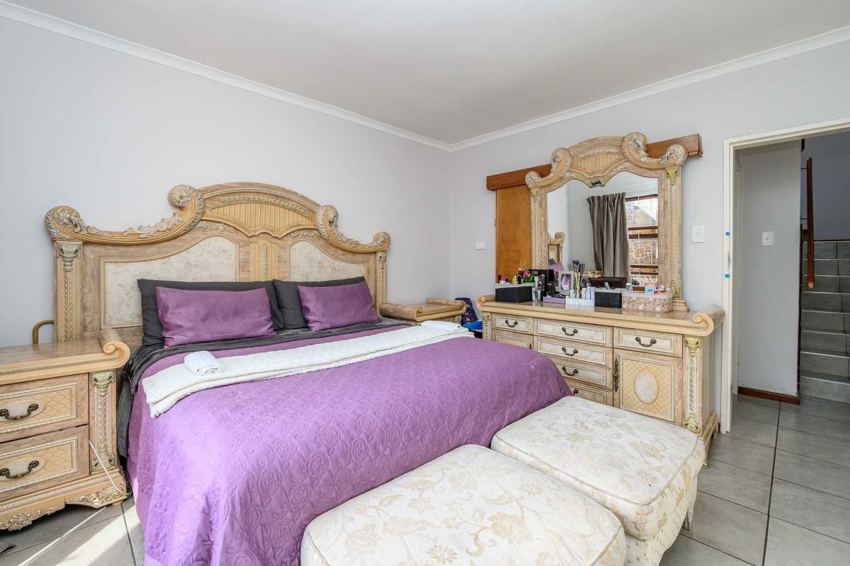 Spacious bedroom featuring neutral wall finishes, tiled flooring, and coved ceiling details, providing a functional and well-lit sleeping area.