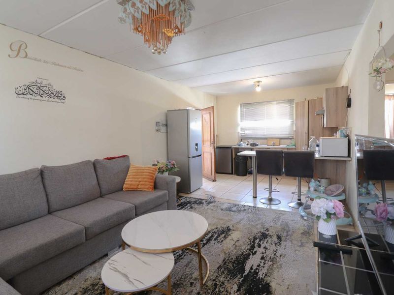 Open plan living and kitchen area featuring tiled flooring, functional cabinetry, and a breakfast bar, offering a versatile space for daily living.