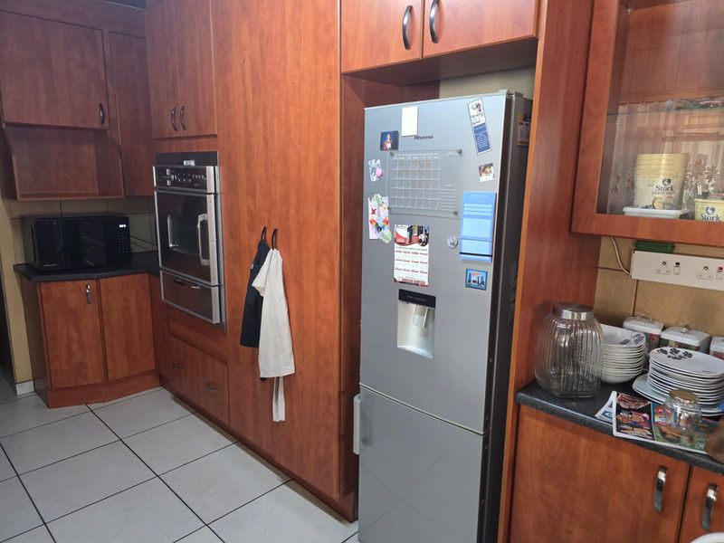 A functional kitchen featuring warm-toned laminate cabinetry, built-in oven, tiled flooring, and ample storage space with a classic layout.
