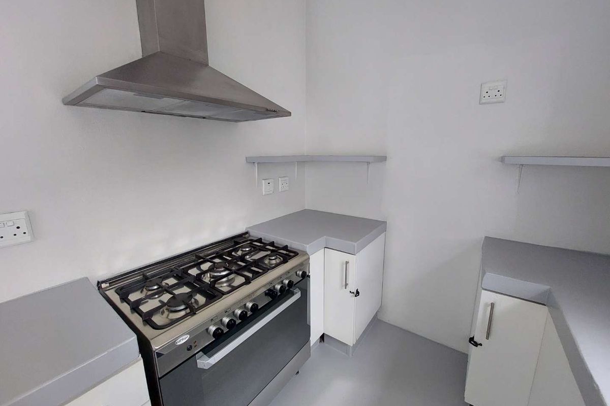 A clean, functional kitchen area featuring a stainless steel gas stove, extractor fan, built-in cabinetry, and ample countertop space.