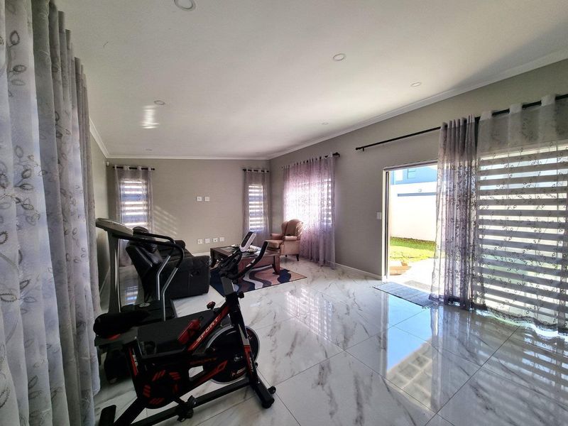 Spacious living area featuring polished marble-look floor tiles, recessed lighting, and large sliding glass doors providing direct access to the garden.