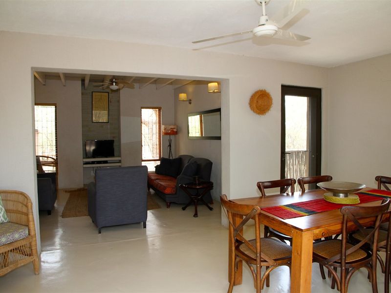 Open plan living and dining area featuring neutral walls, tiled flooring, ceiling fans, and direct access to an outdoor space.