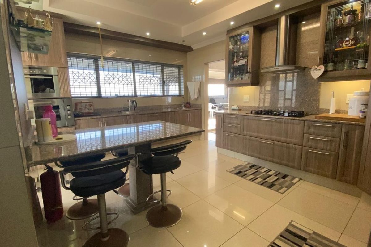 Modern kitchen featuring granite countertops, built-in oven, gas hob, extractor fan, and ample cabinetry with integrated lighting.