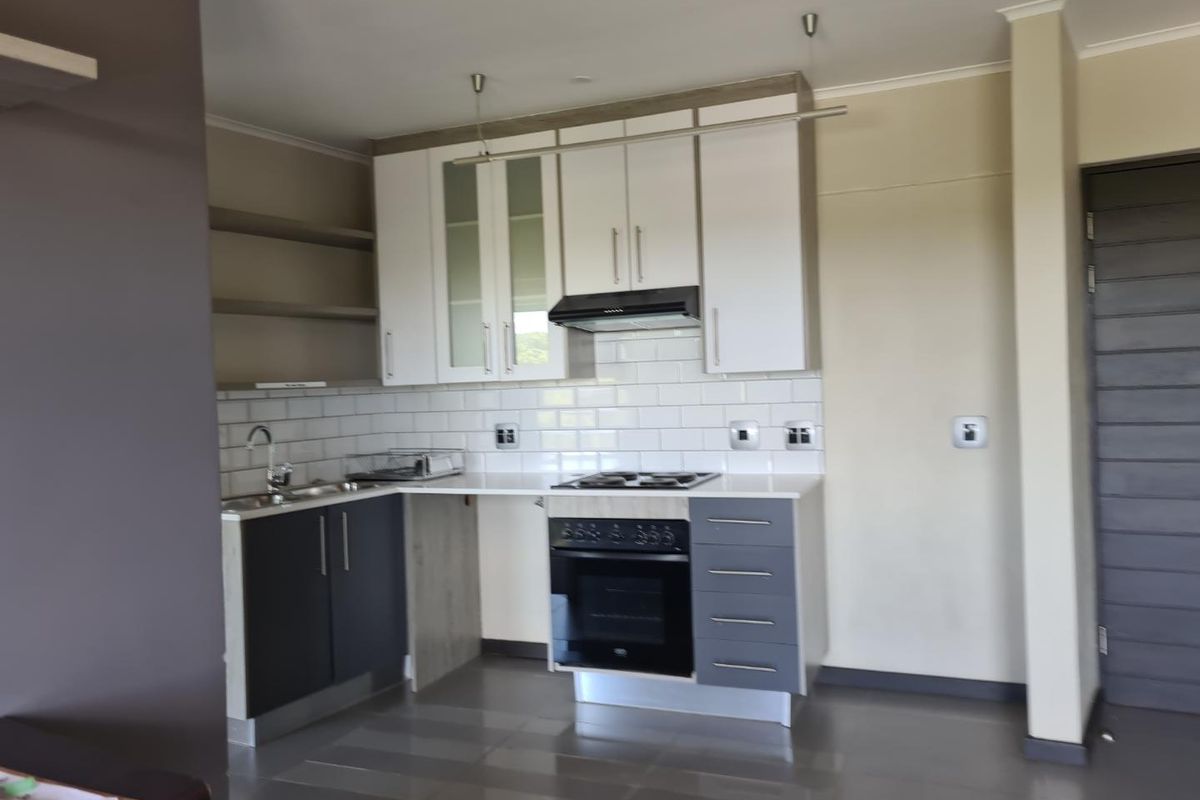 Modern kitchen featuring white and grey cabinetry, subway tile backsplash, built-in oven, and hob with an extractor fan.