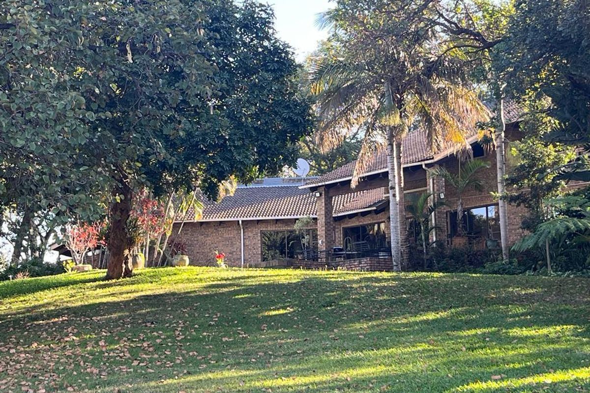A view of the rear brick facade of the property, featuring a tiled roof and established garden surroundings.
