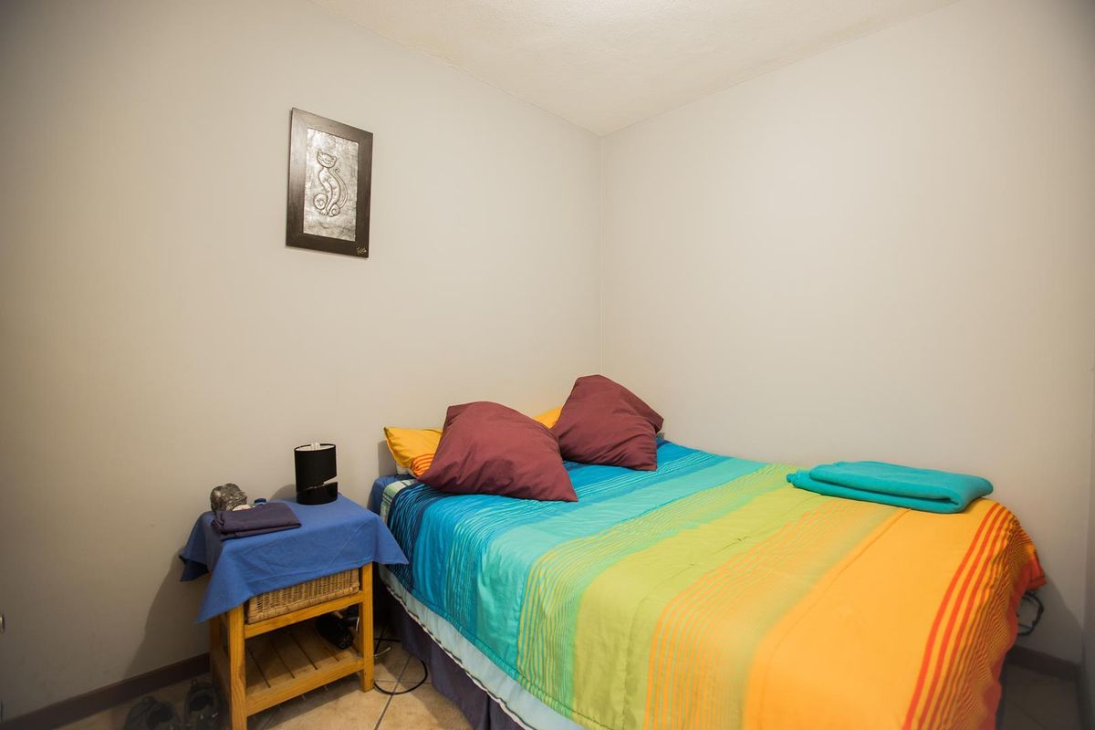 A compact bedroom featuring neutral wall finishes and tiled flooring, providing a functional space for rest.