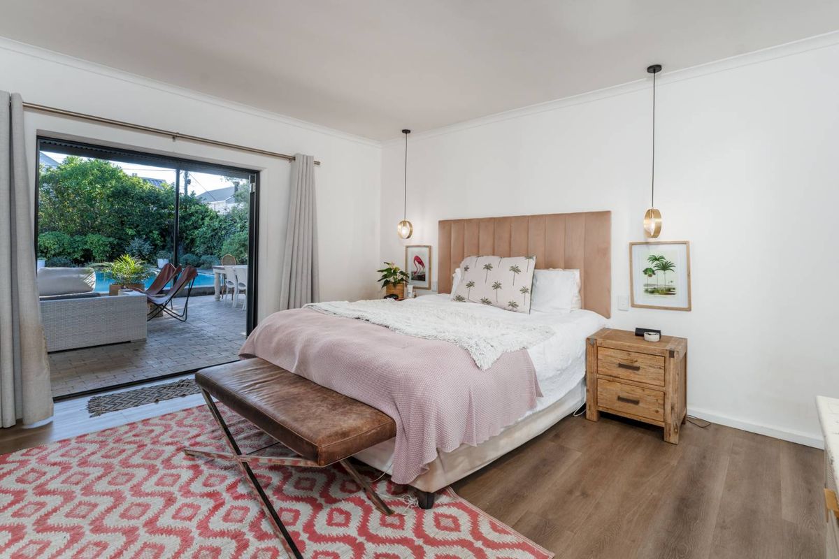 Spacious bedroom featuring modern laminate flooring and large sliding glass doors providing direct access to the outdoor patio and pool area.
