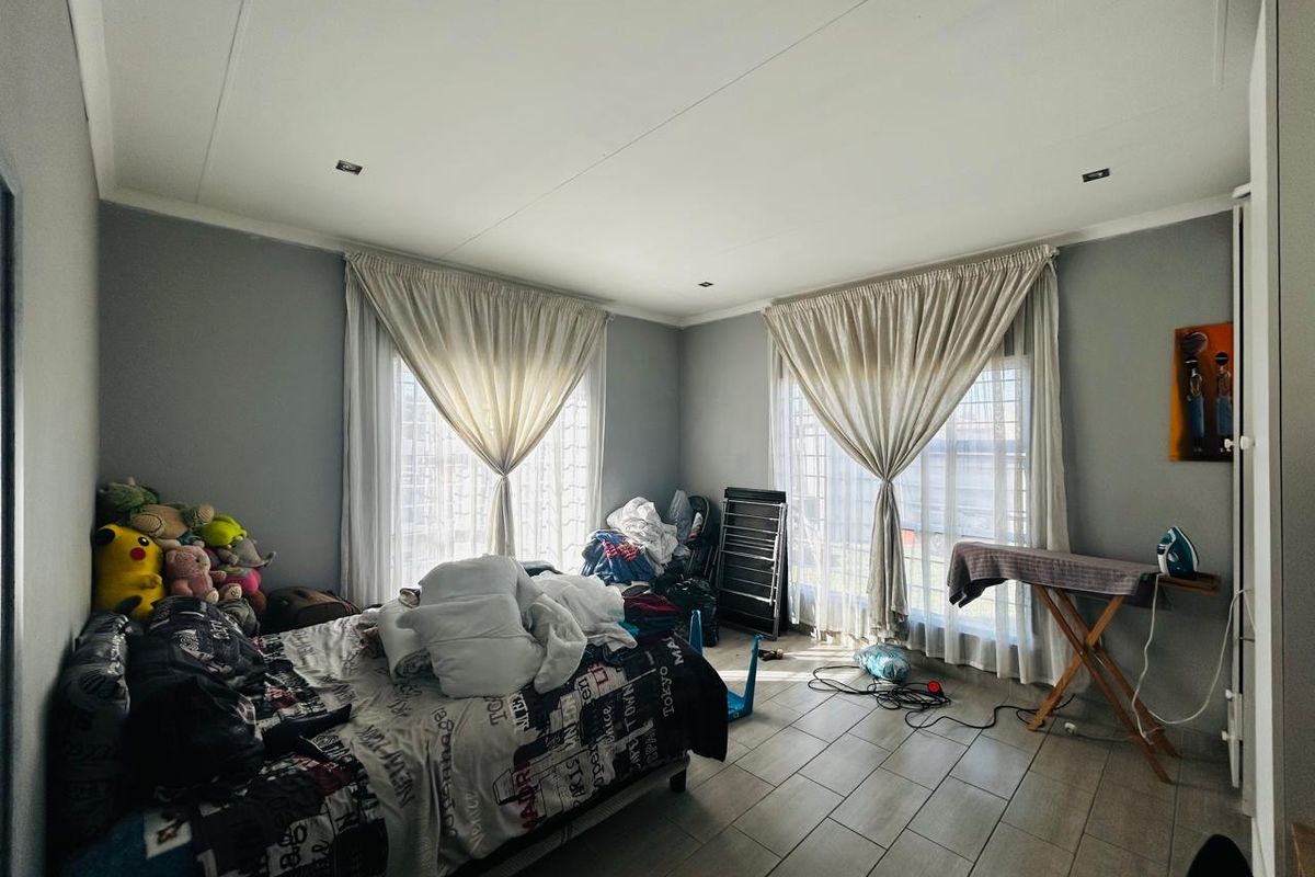 A bedroom featuring tiled flooring, recessed ceiling lighting, and dual windows with fitted curtain tracks.