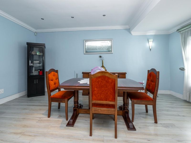 A well-maintained dining room featuring light-toned laminate flooring, coved ceilings, and recessed lighting, creating a bright and functional space for family meals.