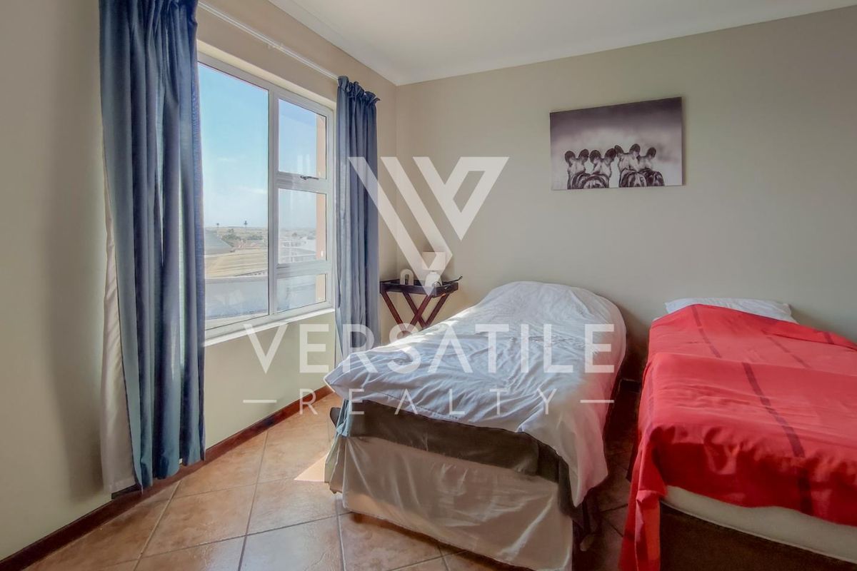 A bedroom featuring tiled flooring and a large window providing natural light and exterior views.