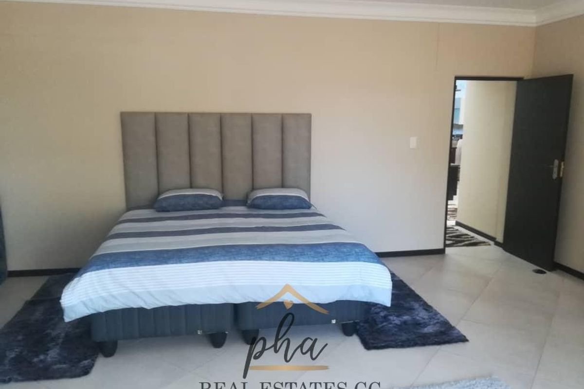 A spacious bedroom featuring neutral wall tones, tiled flooring, and a doorway leading to an adjacent room.