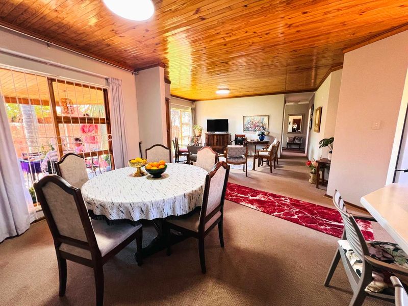 Spacious open-plan living and dining area featuring a distinctive timber tongue and groove ceiling and direct access to the outdoor patio.