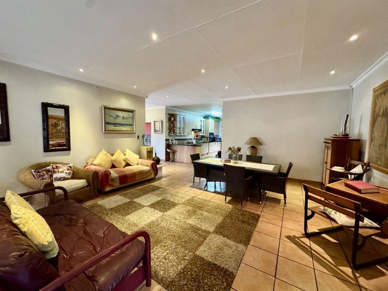 Spacious open-plan living and dining area featuring tiled flooring and recessed lighting, flowing seamlessly into a functional kitchen space.