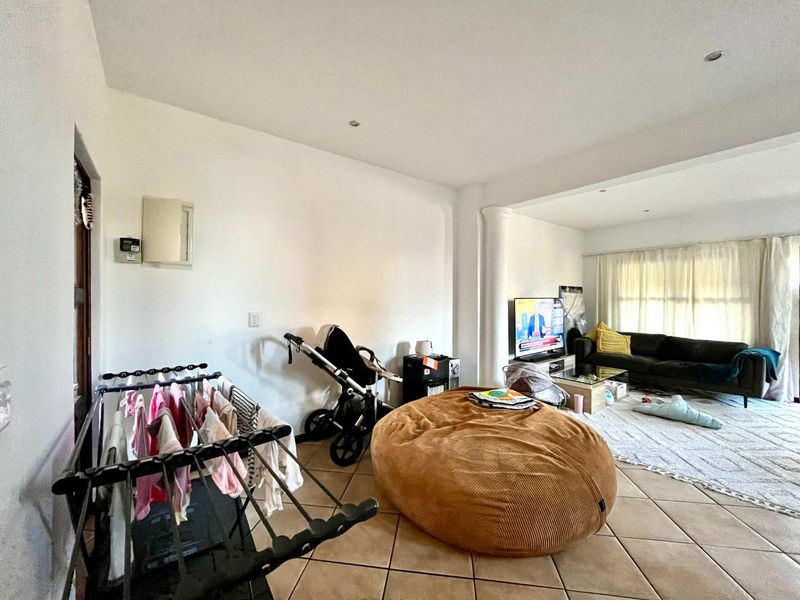 Open plan living area featuring tiled flooring and recessed downlights, providing a versatile space for relaxation and daily activities.