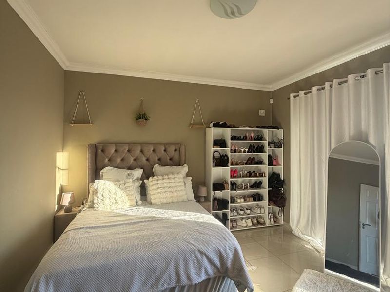 A well-maintained bedroom featuring neutral wall tones, tiled flooring, and coved cornicing, offering a bright and comfortable living space.