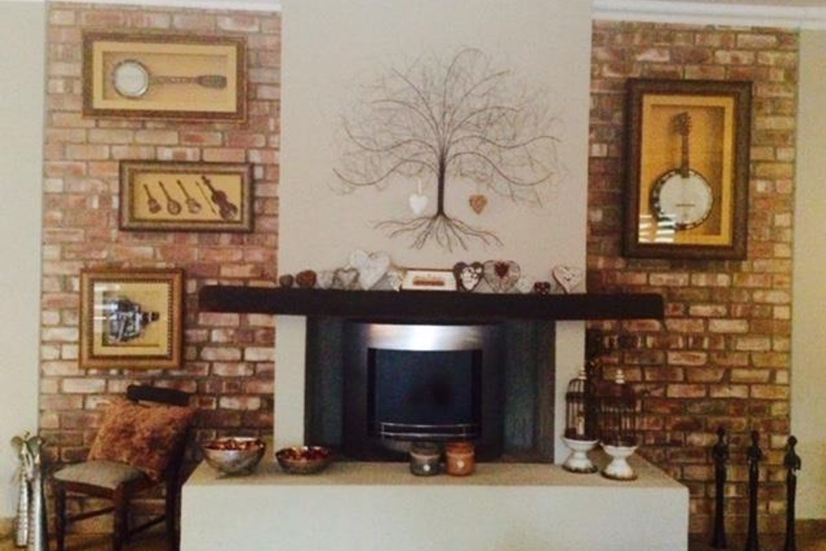 A cozy living room featuring a prominent brick-clad fireplace with a built-in insert and a dark timber mantelpiece.