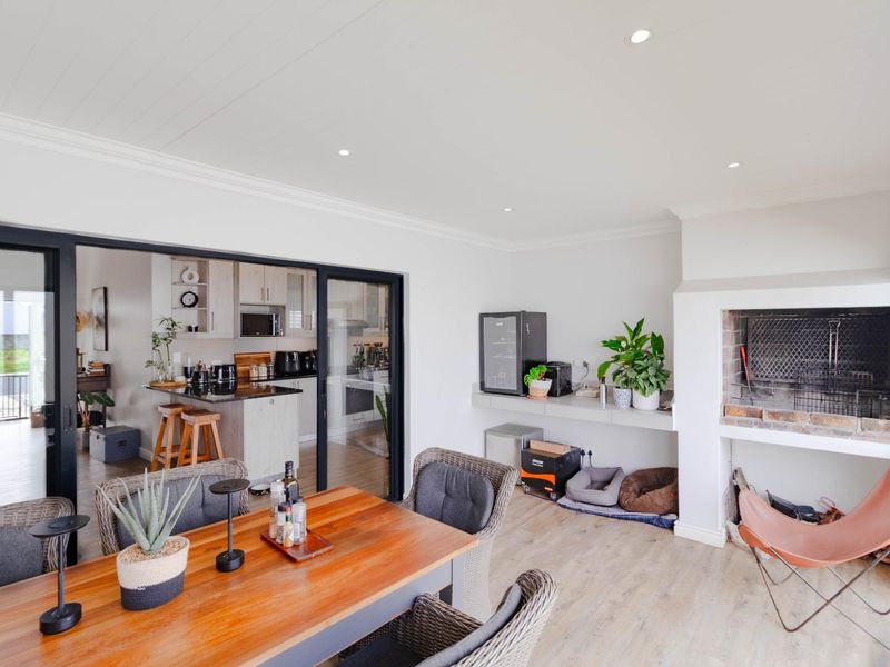 Covered patio area featuring a built-in braai, recessed lighting, and large sliding doors providing seamless access to the adjacent kitchen and living space.
