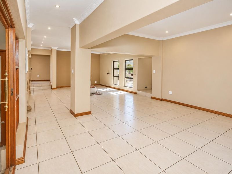 Spacious open-plan living area featuring neutral tiled flooring, recessed lighting, and crown molding, offering a versatile layout with abundant natural light.