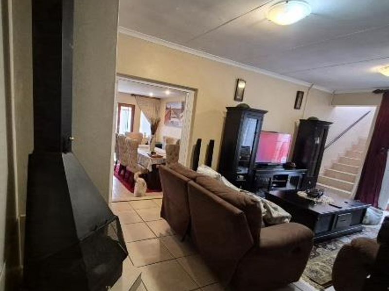 Spacious living area featuring tiled flooring, a prominent freestanding fireplace, and an open-plan layout leading to the dining room and staircase.